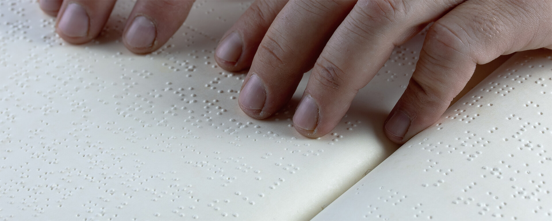 Finger der rechten und linken Hand ertasten Punkte der Brailleschrift.